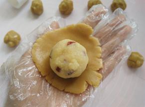 戴上一次性手套，取其中一个面团用2个掌心的摩擦力按扁，放上椰蓉蔓越莓馅