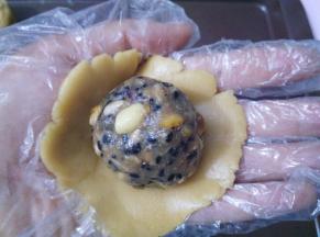 戴上一次性手套，取其中一个面团用2个掌心的摩擦力按扁，放上五仁馅