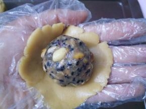 戴上一次性手套，取其中一个面团用2个掌心的摩擦力按扁，放上五仁馅