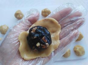 戴上一次性手套，取其中一个面团用2个掌心的摩擦力按扁，放上枣泥馅