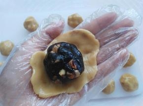 戴上一次性手套，取其中一个面团用2个掌心的摩擦力按扁，放上枣泥馅