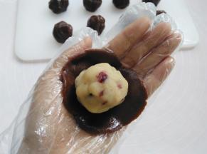 戴上一次性手套，取其中一个面团用2个掌心的摩擦力按扁，放上莲蓉馅