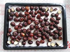 在烤盘上垫上一张锡纸，板栗平铺在锡纸上