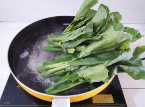 锅里的水烧开后放入15克猪油，2克盐，先放芥兰的根部灼水