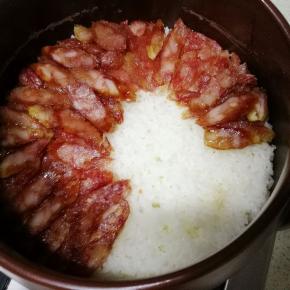 待米饭煮至锅内已无水冒泡后，放入切成片的腊肠，继续小火焖
