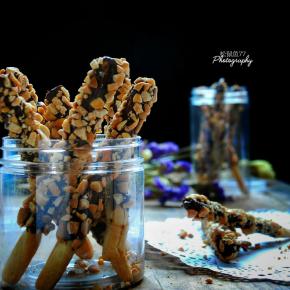 烤好的饼干条裹上巧克力，趁热沾上花生碎，双层百力滋就做好了。