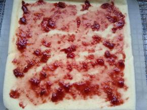 出炉稍微晾凉，倒扣，揭去油布，均匀涂上草莓酱。