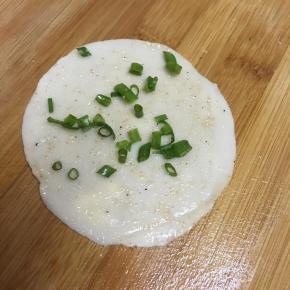 案板抹油，取饺子皮一张，抹上盐和椒盐粉，撒上葱末。