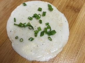 案板抹油，取饺子皮一张，抹上盐和椒盐粉，撒上葱末。