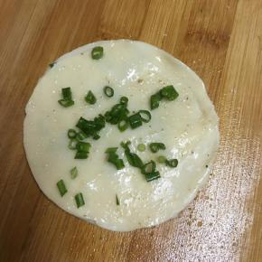再盖上一张饺子皮，同样抹上盐和椒盐粉，撒上葱末。