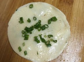 再盖上一张饺子皮，同样抹上盐和椒盐粉，撒上葱末。