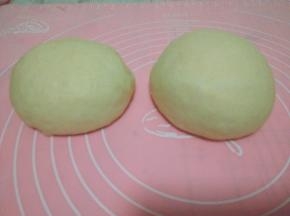 发酵好的面团取出按压排气，分成两份，盖保鲜膜松驰15分钟；