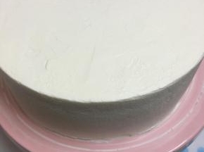 盖上另一片蛋糕片，在蛋糕表面和周边都抹上奶油。