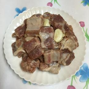 再将腌好的排骨倒入盘中，放入蒜头。