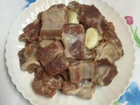 再将腌好的排骨倒入盘中，放入蒜头。