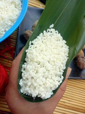 最后上面盖上一层糯米，然后把叶子折过来把糯米盖上，把叶片折好，包紧