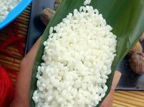 最后上面盖上一层糯米，然后把叶子折过来把糯米盖上，把叶片折好，包紧