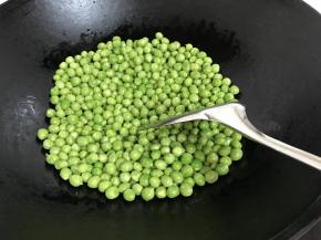 2、锅中倒入适量油，放入豌豆翻炒，加入1小撮盐炒匀后出锅待用。