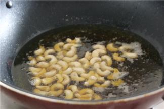 腰果捞出擦干表面的水分，热锅冷油，放入腰果