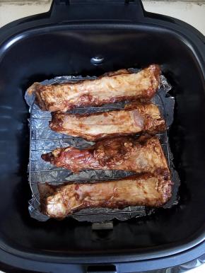 将利仁空气炸锅的内胆中铺上一层锡纸，这样可以使清洁更简单而且底部有锡纸也有利于热循环，排骨放在烤架上。