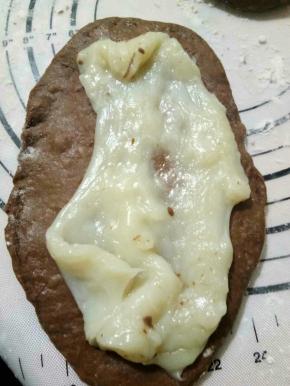 发酵好的面团，取出排气。分成3份，一份160g左右，麻薯也分成3份，取一块面团擀开，把麻薯也擀成差不多大小的，