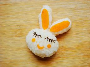 海苔剪细条摆放出眯起的眼睛和长长的睫毛，用裱花嘴刻出两个胡萝卜小圆片做红脸蛋，月牙状做嘴巴。