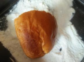 抹好奶酪的面包放盛有奶粉、糖粉混合物中沾一下，使之粘上奶糖粉；