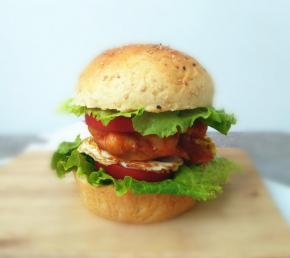 抹上番茄酱和沙拉酱，夹入生菜、番茄、煎蛋和鸡腿肉。美味的巨无霸鸡腿堡就成功喽。