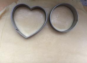 案板铺保鲜膜，把面团放保鲜膜上，再盖一张保鲜膜，然后用擀面杖擀平，厚度约5毫米，用各种压膜压出片片。烤箱预热180度。