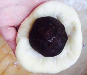 面团按瘪，包包子一样，包一个豆沙球进去，包口在下