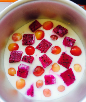 先倒入一层奶酪糊，放几颗樱桃和火龙果