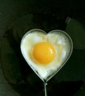 锅里倒入少许油，煎蛋器内测也抹上一层油。待油锅稍热，打入鸡蛋，煎一两分钟后翻面。