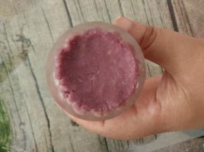 最后取一个紫色圆球放进月饼模具中，用手稍微压扁。