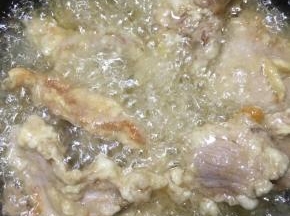 锅中加入多一些的油，大火烧至8分热，下入肉片中火炸至呈金黄色捞出。