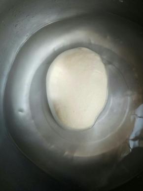 取一个大点的盆倒入半盆清水，将面团泡入水中