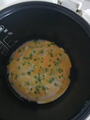 按下煮饭键，盖上盖子 1分钟后开盖到， 将蛋黄戳破 ，在饼上倒上适量鸡蛋液，盖上锅盖， 继续加热