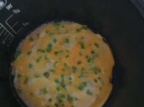 按下煮饭键，盖上盖子 1分钟后开盖到， 将蛋黄戳破 ，在饼上倒上适量鸡蛋液，盖上锅盖， 继续加热