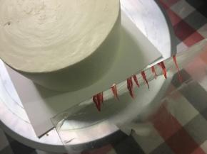 用软刮片修整过的抹面会漂亮很多……蛋糕纯白感觉单调了点，所以我在软刮刀上弄点红色色素，然后抹在蛋糕侧面，做成间色效果