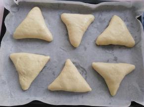 把所有的面团包成糖三角形状，收口朝下，放进烤盘里，间隔开一定的距离