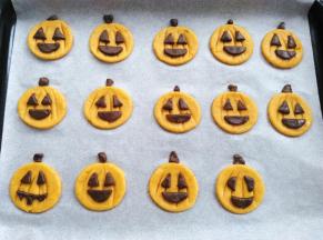 把可可面团分割出来的嘴巴，眼睛沾点水贴到南瓜饼胚上，多出来的一些小碎料用来做南瓜柄，同时预热烤箱160度