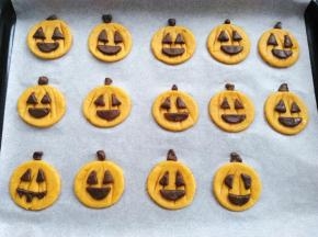 把可可面团分割出来的嘴巴，眼睛沾点水贴到南瓜饼胚上，多出来的一些小碎料用来做南瓜柄，同时预热烤箱160度