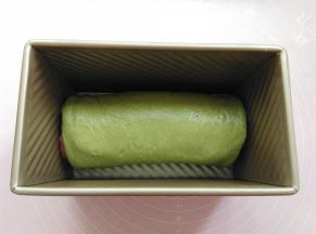 把卷好的面团放到土司盒里，放进烤箱发酵