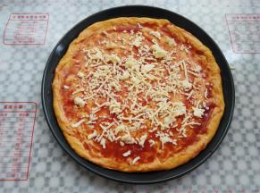 披萨饼皮上抹上一层番茄酱，放入少量马苏里拉芝士碎