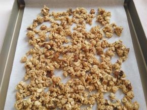 烤盘里垫上油纸，把混合好的麦片铺在油纸上，尽量均匀分开一点，预热烤箱160度
