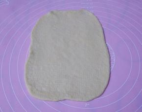 取一个面团擀成长方形，松弛过的面团比较容易擀，觉得不太好擀的可以换一面再擀平，宽度不要太长，以超出火腿肠1-2厘米最合适