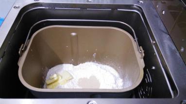 把主配方中所有材料按照先液体再粉末的顺序放进面包桶内，黄油放一侧，选择面包机发面程序。