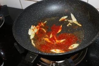 锅内留底油，大火爆香葱姜。
放入两勺番茄酱翻炒均匀。