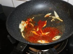 锅内留底油，大火爆香葱姜。
放入两勺番茄酱翻炒均匀。