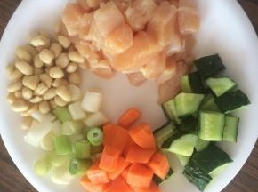 准备食材，鸡胸肉切成1cm左右的小块，黄瓜、胡萝卜切小丁。花生提前用开水浸泡5分钟，剥去外皮。