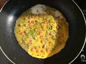 煎到面糊半透明的时候淋上一层蛋液，再撒适量的野葱碎